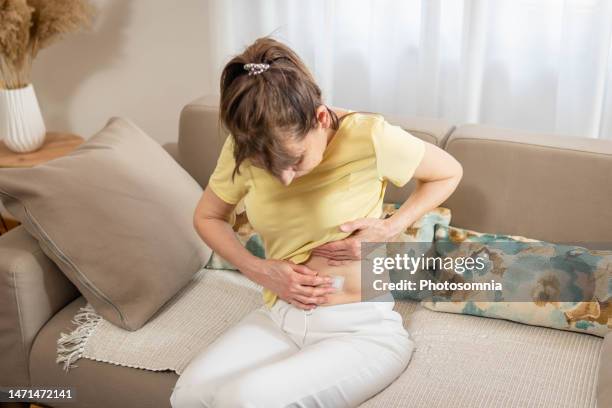 mature woman applies transdermal patch - oestrogen stock pictures, royalty-free photos & images