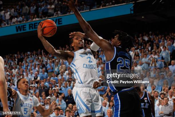 Caleb Love of the North Carolina Tar Heels goes to the basket under pressure from Duke Blue Devils forward Mark Mitchell on March 04, 2023 at the...