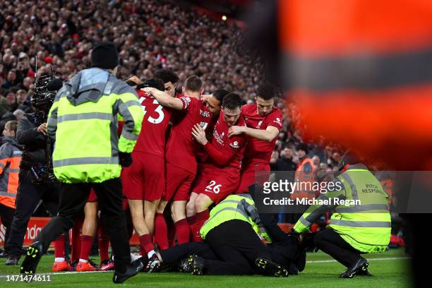 Pitch invader is tackled by stewards after colliding with Andrew Robertson of Liverpool as players of Liverpool celebrate after Roberto Firmino of...