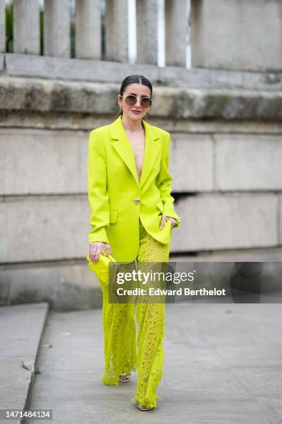 Alexandra Pereira wears black sunglasses, gold earrings, a yellow blazer jacket from Elie Saab, matching cut-out print pattern flared pants, a yellow...