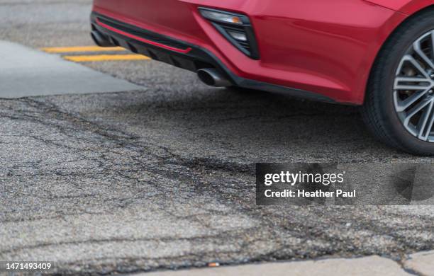 red car driving past a pothole on a city street - bloomington illinois stock pictures, royalty-free photos & images