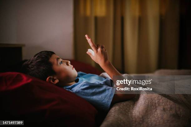 late-night screen time: young boy lost in his phone in bed - child sleeping stock pictures, royalty-free photos & images