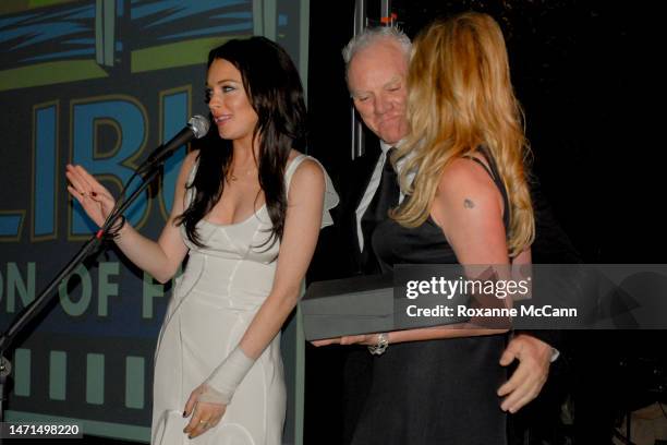 Actress Lindsay Lohan makes a speech accompanied by actor Malcolm McDowell and actress Virginia Madsen at The Malibu Celebration of Film Gala in...