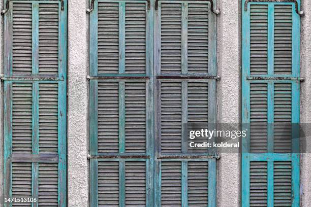 closed teal colored old wooden jalousies - shabby chic stockfoto's en -beelden