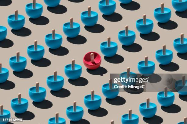a red spinning top stopped among many spinning tops - spinning top stock pictures, royalty-free photos & images