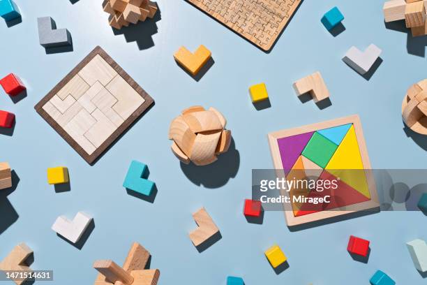 a variety of multi colored puzzle toys flat lay on blue - tangram stock-fotos und bilder