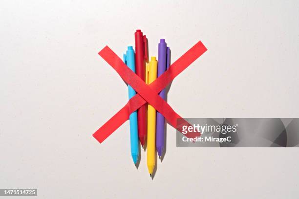 a bunch of pens blocked by red tape cross - exclusion concept stock pictures, royalty-free photos & images