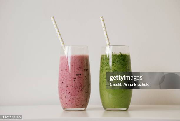 two glasses of green spinach and pink berry smoothie on white table. healthy vegan diet concept. fresh organic drink. - smoothie bildbanksfoton och bilder