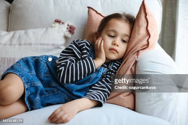 niña enferma tosiendo en el sofá - headache child fotografías e imágenes de stock