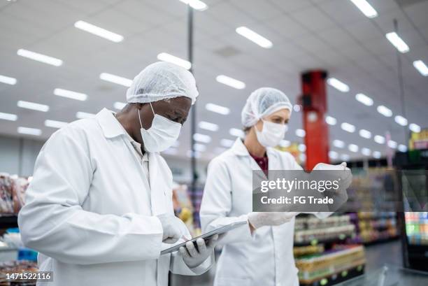 inspektoren analysieren die lebensmittel im supermarkt - food safety stock-fotos und bilder