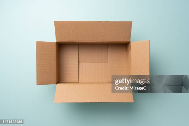 opened empty cardboard box on blue background - cardboard box photos et images de collection