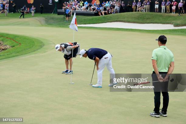 Kurt Kitayama of The United States examines his golf ball as his long putt came to rest less than an inch from the hole on the 18th green to secure...