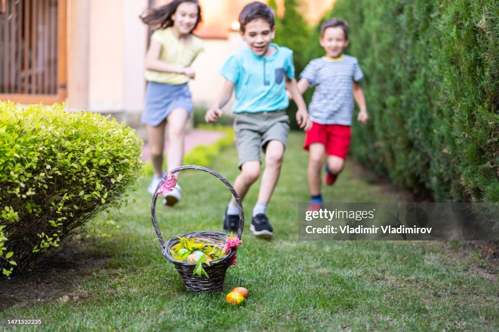 Children running towards an Easter basket on the ground