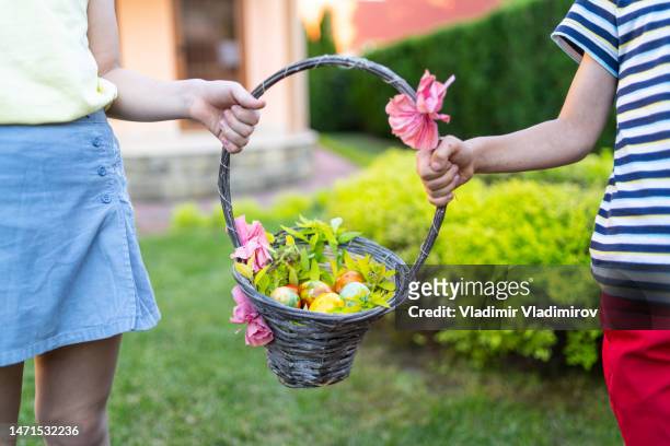 two unknow children holding an easter basket between them - easter basket with candy stock pictures, royalty-free photos & images