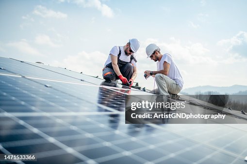 Team von zwei Arbeitern auf dem Dach eines Hauses, die Sonnenkollektoren installieren. Team von zwei Arbeitern auf dem Dach eines Hauses, die Sonnenkollektoren installieren.