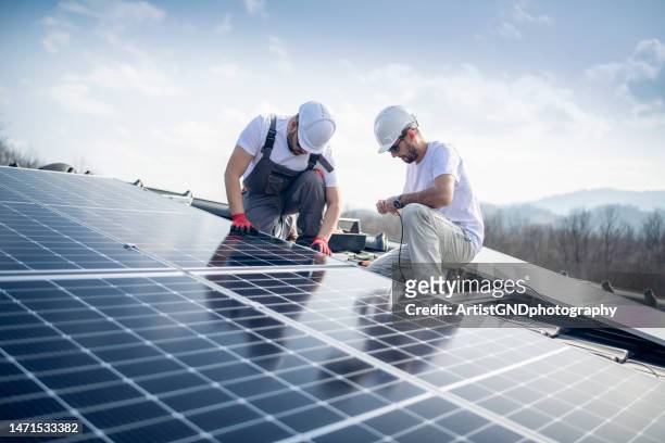 trabalhadores instalando painel solar no telhado da nova casa. - energia solar - fotografias e filmes do acervo