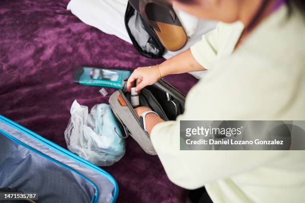 person preparing a toiletry bag next to a suitcase - amenities hotel stockfoto's en -beelden