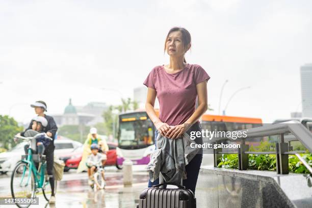 woman with luggage waiting for bus. - asian waiting angry expressions stock pictures, royalty-free photos & images