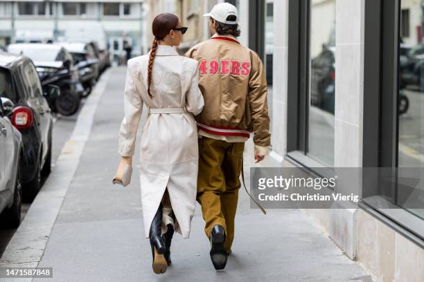 Couple Sebastien Roques wears brown bomber jacket, pants, cap & Alice Barbier wears belted creme white coat, Loewe bag outside Ottolinger Paris...