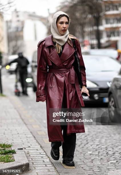 Guest is seen wearing a maroon leather trench coat and a cream head scarf outside the Akris show during Paris Fashion Week F/W 2023 on March 05, 2023...