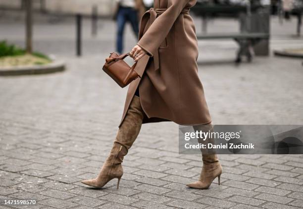 Guest is seen wearing a tan coat, white turtleneck, brown boots and brown mini-bag outside the Akris show during Paris Fashion Week F/W 2023 on March...