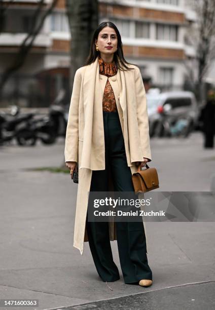 Julia Haghjoo is seen wearing a yello coat, brown floral top, green pants and brown bag outside the Akris show during Paris Fashion Week F/W 2023 on...