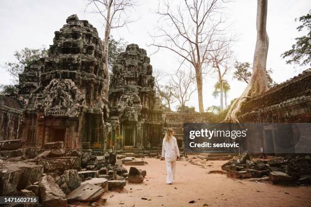 traveler exploring ancient ruins of ta prohm temple at angkor - cambodjaanse cultuur stockfoto's en -beelden