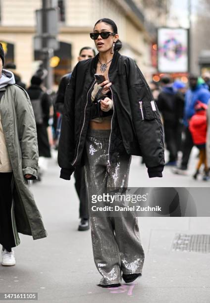 Guest is seen wearing a black bomber, cream crop top, silver pants and a black mini-bag outside the Palm Angels show during Paris Fashion Week F/W...