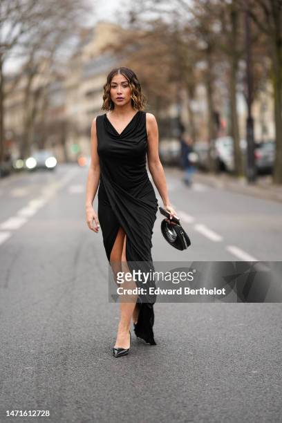 Guest wears a black V-neck / sleeveless long tube slit / split dress, a black shiny leather handbag, black shiny leather pointed pumps heels shoes...