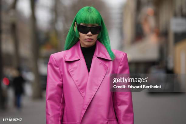 Guest wears black futurist sunglasses, a black turtleneck wool pullover, a neon pink shiny leather oversized blazer jacket, outside Palm Angels,...