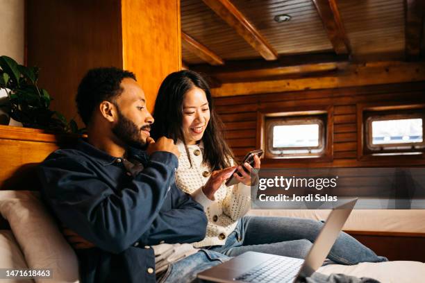 couple using laptop in a sailing boat cabin - passenger cabin stock pictures, royalty-free photos & images