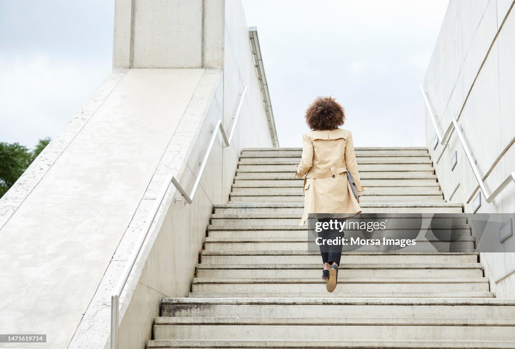 Full length of businesswoman moving up steps