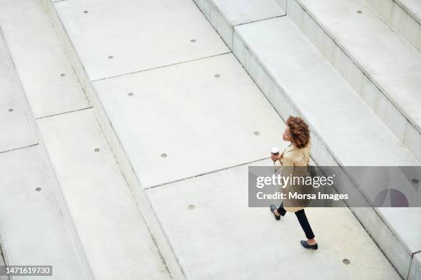 businesswoman looking away while walking on steps - city life stock pictures, royalty-free photos & images