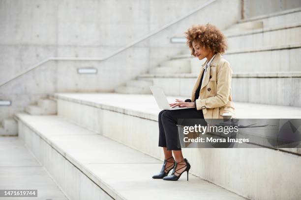 businesswoman using laptop while sitting on steps - steps side view stock pictures, royalty-free photos & images