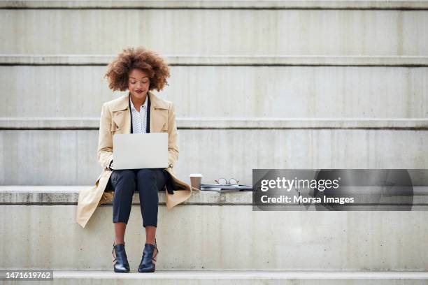 young businesswoman using laptop on steps - business person laptop foto e immagini stock