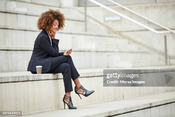smiling businesswoman using smart phone on steps - smart shoes stock pictures, royalty-free photos & images