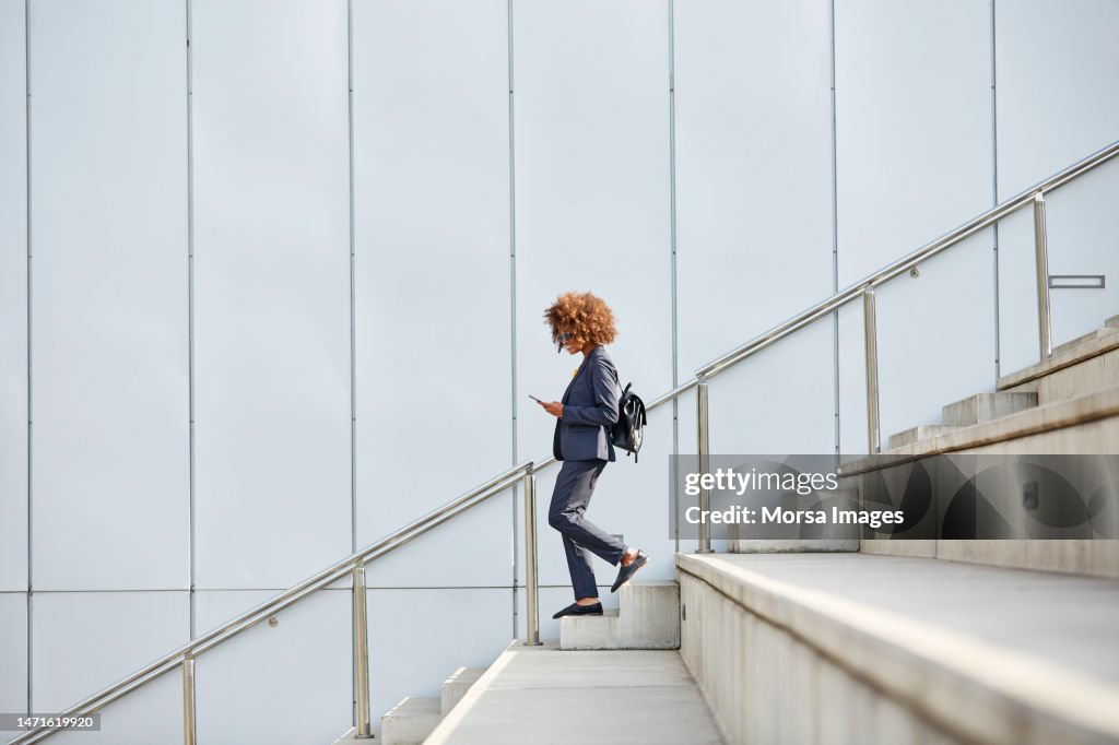 Businesswoman using smart phone on staircase