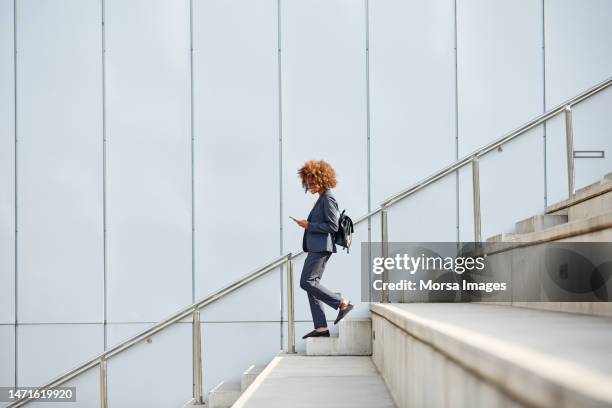 businesswoman using smart phone on staircase - descente stock pictures, royalty-free photos & images