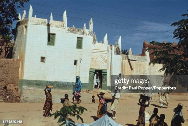 Pedestrians pass and children congregate in front of a wealthy man's house in Kano, capital city of Kano State in northern Nigeria circa 1950.