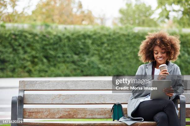 young businesswoman using digital tablet on bench - springtime city stock pictures, royalty-free photos & images