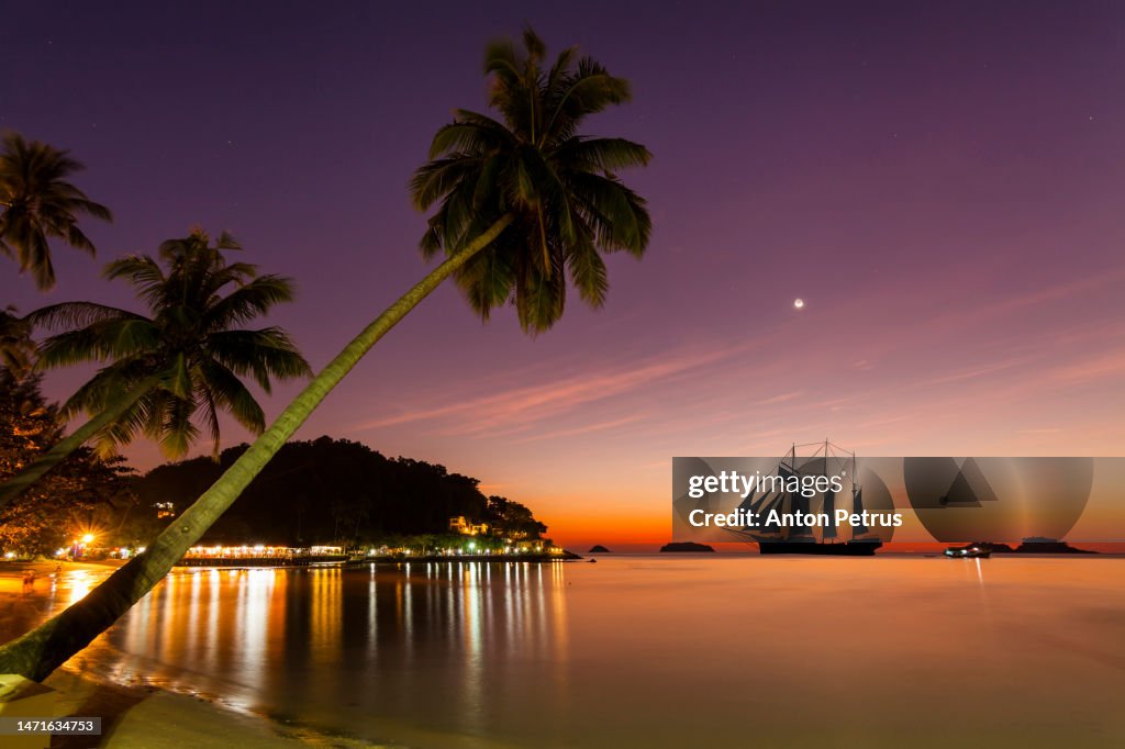 Sailboat at sunset near the shores of a tropical island
