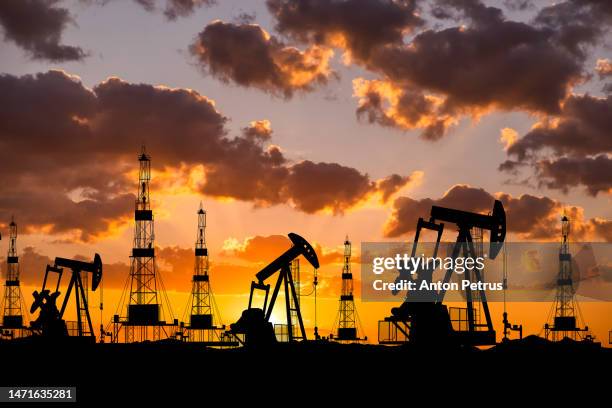 oil field with rigs and pumps at sunset with the road. world oil industry - drillinge stock pictures, royalty-free photos & images