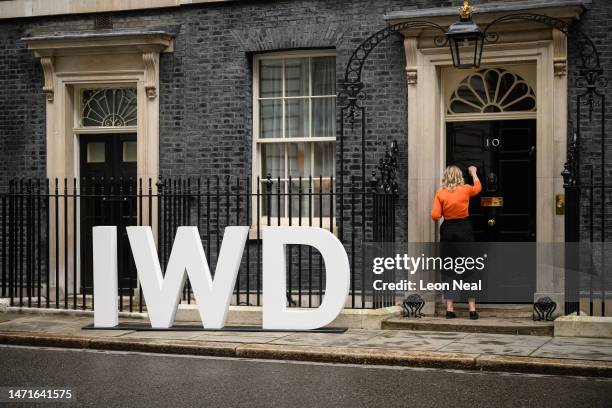 Sign for International Women's Day is seen as a woman knocks on the door of number 10 Downing Street on March 06, 2023 in London, England....