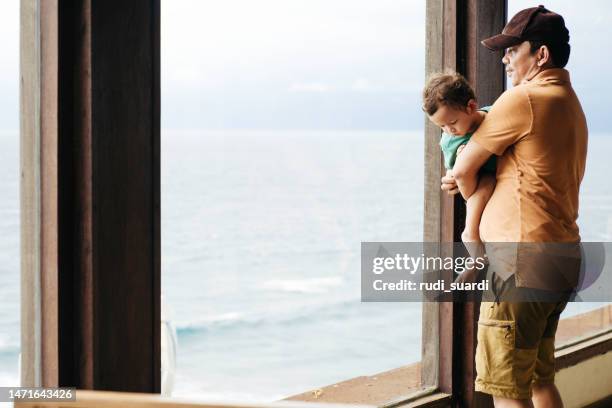 asian man carrying his child looking thorough on window - beach balcony stock pictures, royalty-free photos & images