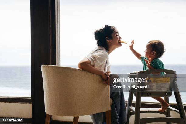 椅子に座ってピザを食べる息子を持つアジア人女性 - リゾート　家族 ストックフォトと画像