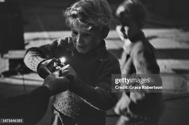 Scottish child actor Jon Whiteley using a cigarette lighter during production of Charles Crichton's drama, 'Hunted', 1951. Original Publication:...