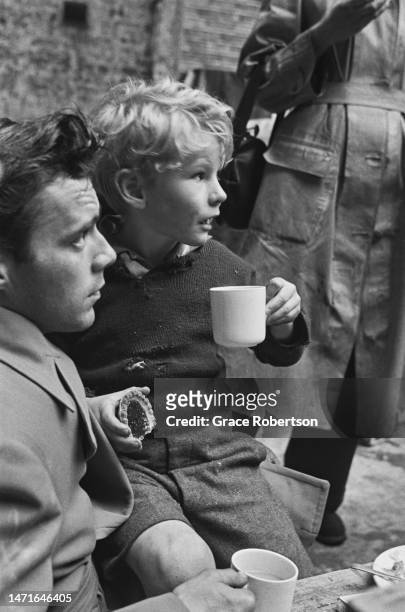 English actor, Dirk Bogarde and Scottish child actor, Jon Whiteley stop for a refreshment break during production of Charles Crichton's drama,...