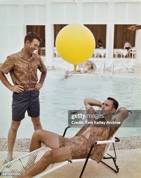 American golfer Ken Venturi with basketball player Bob Cousy, Hawaii, 1962. Cousy is using a straw to drink from a Coca-Cola bottle suspended from a...