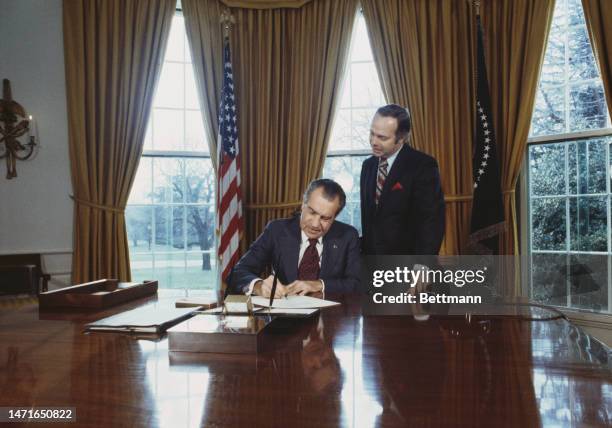 President Richard Nixon signs the 'Daylight Saving' Act at the White House In Washington on December 15th, 1973. He is watched by Representative...