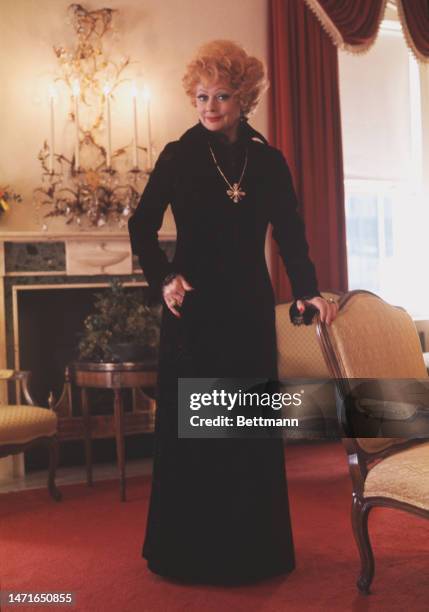 American actress Lucille Ball poses in a floor-length black dress in her suite at the Waldorf Towers hotel in New York on March 6th, 1974.